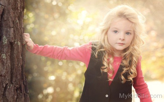 Girl Peeking Around A Tree